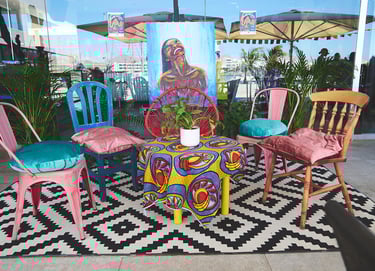 Una mesa colorida con sillas y una mesa con una planta en maceta.