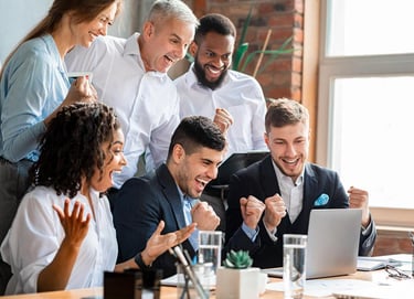 a group of people sitting around a table with a laptop
