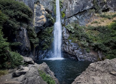 Imponente caída de agua rodeada de bosque nativo y vegetación en la ruta de cascadas de Lonquimay.