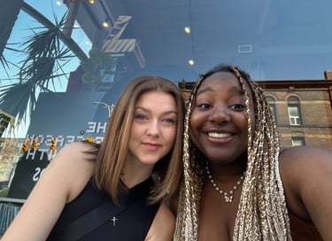 Two girls sitting in front of a store window