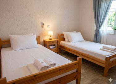 Two single wooden beds with white linens and a nightstand in a bright hotel room.