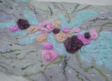 Handmade nuno felted wool scarf featuring intricate 3D silk fabric flowers in pink and purple tones.