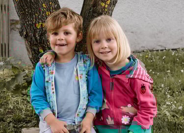 zwei Kinder die sich umarmen auf einer Bank