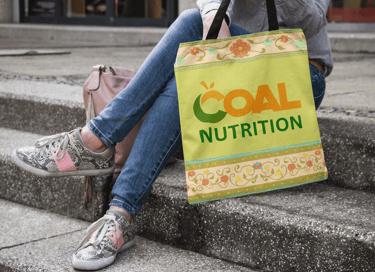 Une femme assise sur des marches tenant un sac avec le logo nutrition orné de motifs floraux.