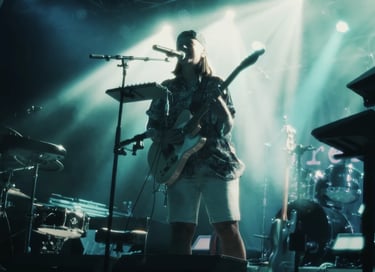 Musician playing electric guitar and singing at a live concert with dramatic stage lighting.