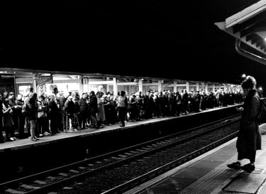 Two platforms at a train station, with one person on the nearside and hundreds on the other.