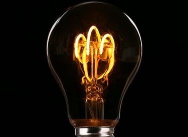 A glowing light bulb with visible filament against a black background.