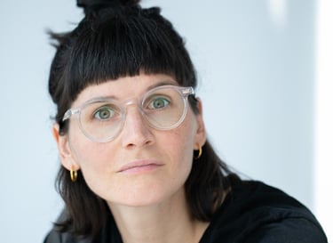 eine Frau mit Brille und schwarzen Haaren, die zum Zopf hochgesteckt sind