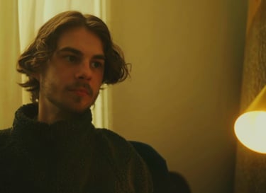 a man in a black sweater and a light bulb on a lamp