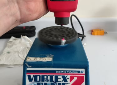 agitador vortex en calibración con tacómetro sobre mesa de laboratorio