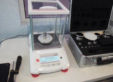 balanza analitica en calibración con juego de pesas al lado