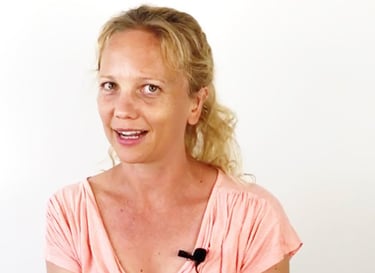 eine Frau mit rosa Hemd und einem schwarzen Ansteckmikrofon