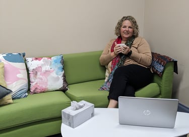 a woman sitting on a couch with a laptop and a coffee table