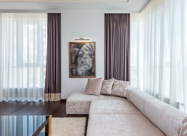 Modern living room featuring a plush sectional sofa, dark wood floors, and elegant purple curtains.
