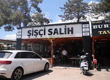 Sisci Salih restaurant storefront in Turkey with outdoor seating, a white car, and a blue scooter.