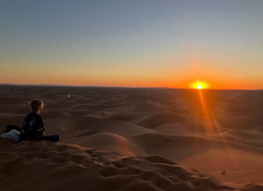 Traveller seated on Erg Chigaga dune at sunset, Morocco’s largest sand sea