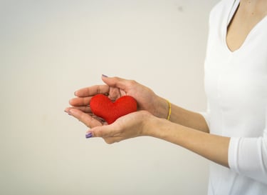 Femme tenant dans sa main un cœur rouge, symbole d'entraide et de soutien