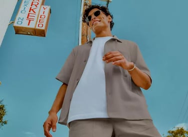 A man wearing an outfit from lululemon: beige collared shirt, white t-shirt, and beige shorts.