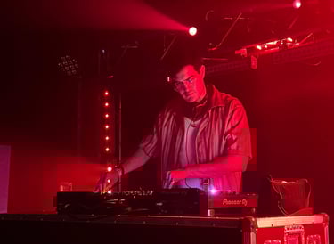 a man in a red shirt is djing in a stage