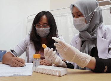 Tenaga peneliti laboratorium menganalisis sampel darah dalam tahap analisis data uji klinis