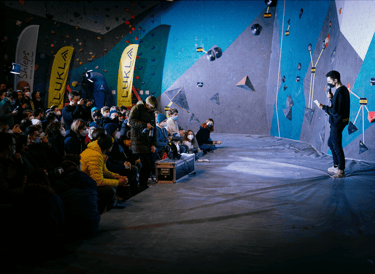 a man standing near a climbing wall in front of a crowd