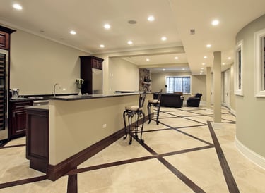 Modern finished basement featuring a wet bar with dark wood cabinets and unique diamond pattern tile flooring.