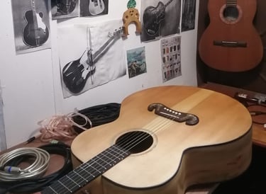 Guitarra elaborada artesanalmente en mesa de trabajo con herramientas y repuestos. lutheria