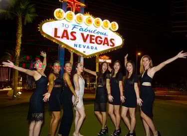 A group of women celebrating a bachelorette party at the Welcome to Fabulous Las Vegas sign at night.