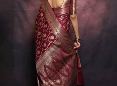 Woman wearing an elegant maroon Banarasi silk saree with intricate gold floral zari embroidery.