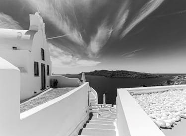 a black and white photo of a house with stairs leading to a balcony
