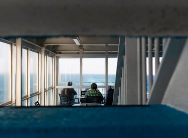 a man and woman sitting at a table with a view of the ocean