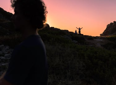 a man standing on a hill with his arms up in the air