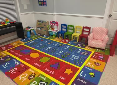 Daycare playroom with colorful abc mat, chairs and reading corner