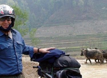 Backpacker with a motorcycle and waterbuffalo in the background