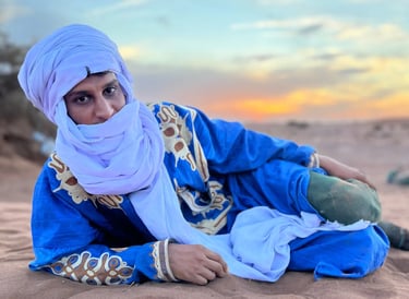 Hssein Liaichi, wearing traditional nomad dress, lying in the desert on a Moroccan camel trek