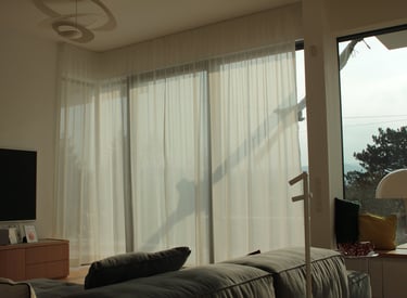 A big window hanged with wavy day curtains