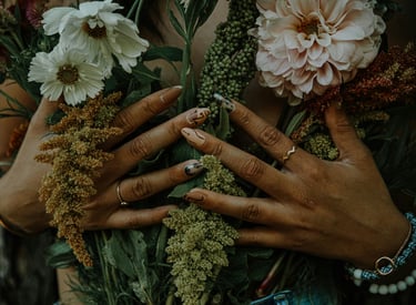 Une femme les mains vernies sur la poitrine, tenant un bouquet de fleurs.