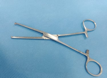Pinça Kocher reta sobre tecido azul estéril, usada para fixar tecidos firmes.