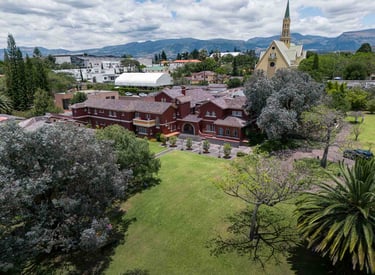 Fotografía aérea de gran casa religiosa de color rojo rodeada de hermoso  jardín verde en Quito Ecuador