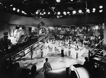 Berkeley on a crane with camera crew, filming white‑skirted dancers in geometric layout.