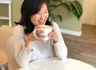 a woman is smiling and holding a cup of coffee