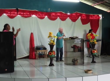 Pastor Esmerito Reyes stands behind a podium preaching to a congregation.