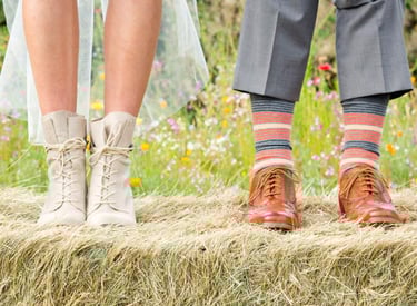 the feet of a couple of people standing on hay bale