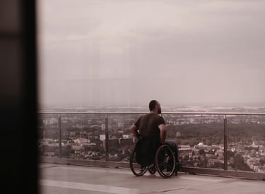 Mann mit Rollstuhl ist auf einem Hotel-Balkon und schaut über eine Stadt