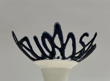 A blue glass bowl sculpture in the shape of a line of text, sitting on a porcelain ceramic pedestal