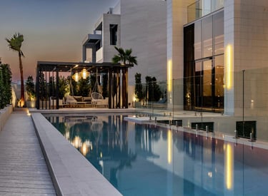 Outdoor poolside lounge area with hanging chairs and greenery at sunset.