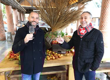 two men standing next to each other holding wine glasses