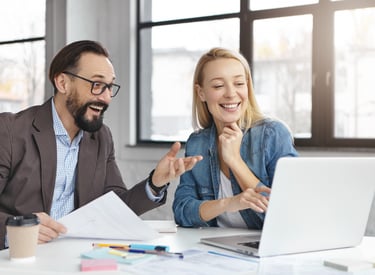 a man and woman sitting at a table with papers