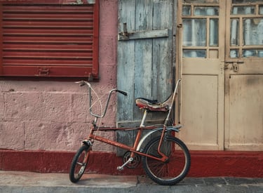 An old bicycle leaning against a weathered wooden door and wall with contrasting colors in Port Louis, Mauritius