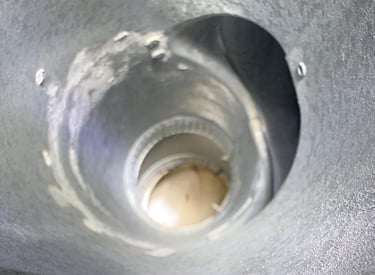 A view from inside a dirty and worn metal chimney flue, highlighting the need for a professional cleaning and inspection by R